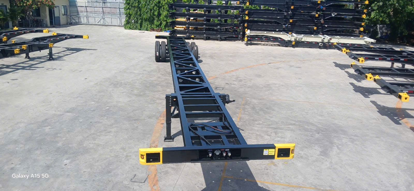 Rows of black skeletal container chassis with yellow safety markers on the Kotinochi production yard